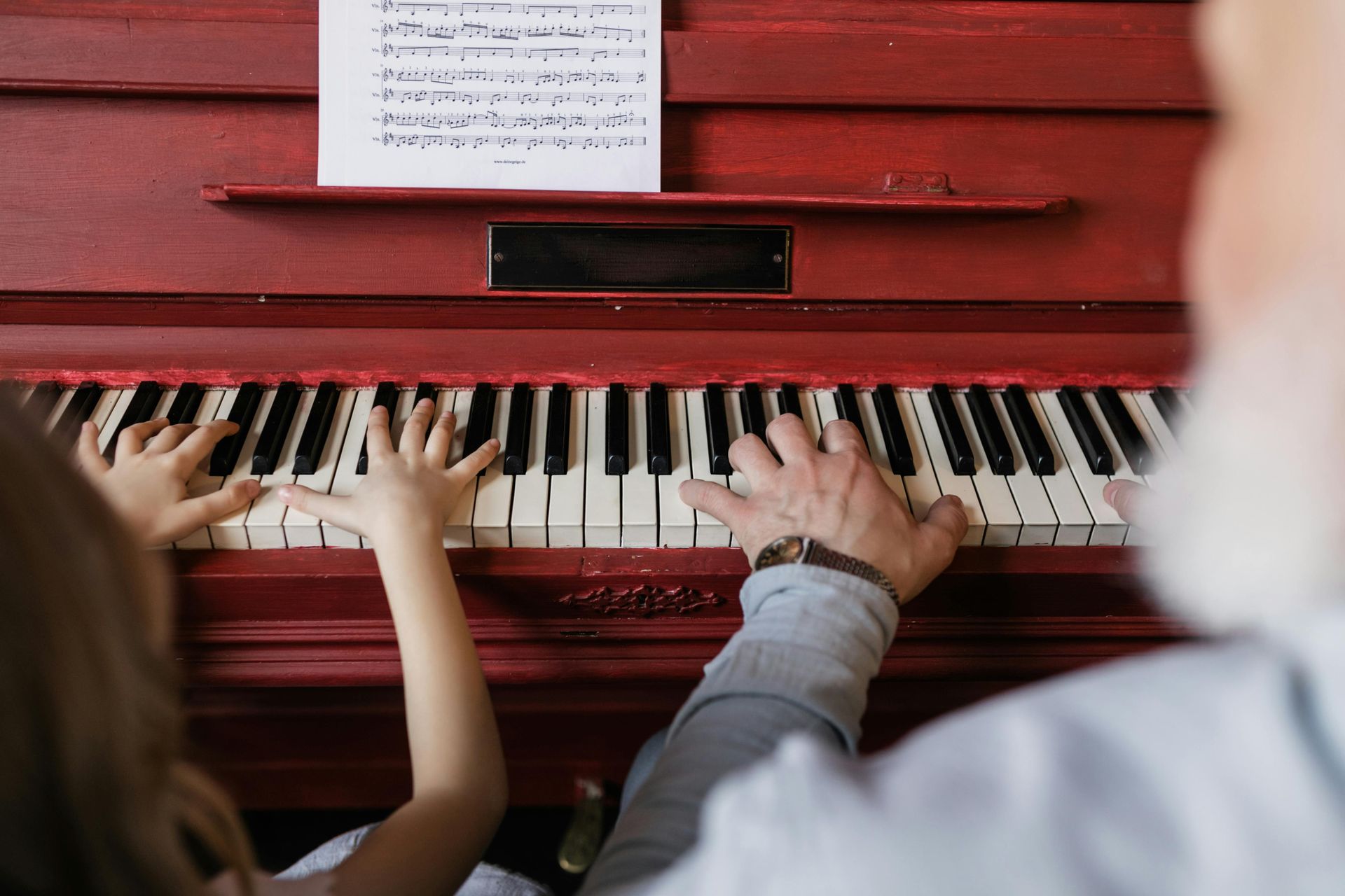 Viva a música que há em você! Criança e adulto juntos, tocando piano.