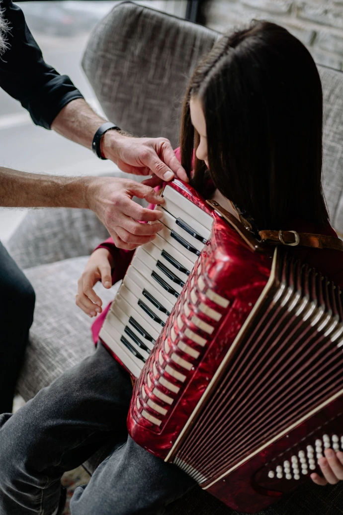 Menina com seu professor de acordeon, aprendendo o dedilhado musical.